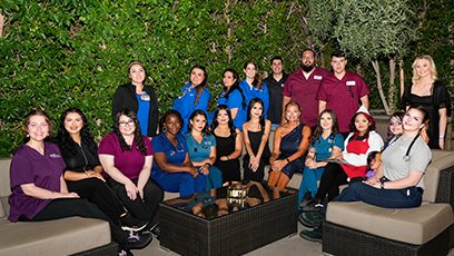 Group of students wearing scrubs sitting on an outdoor couch.