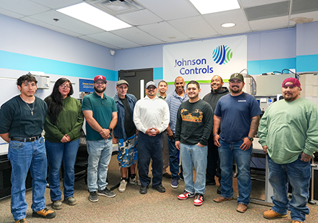 Group of diverse students standing in a classroom with banner with "Johnson Control" behind them