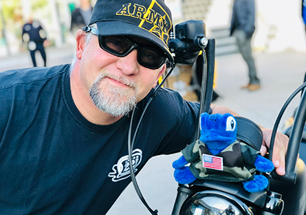 Dr. Joseph Swaba poses with a plush Echo the Gecko sitting on the front of his motorcycle.