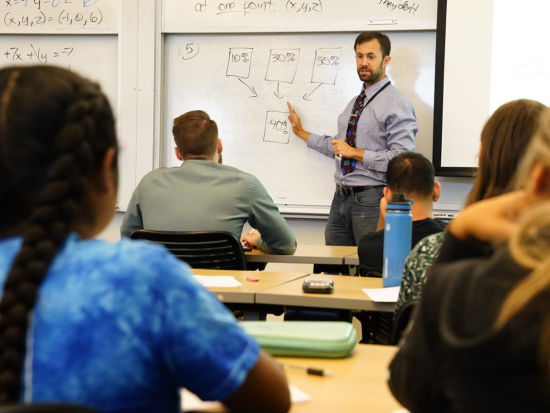 male teacher at the whiteboard instructing a class