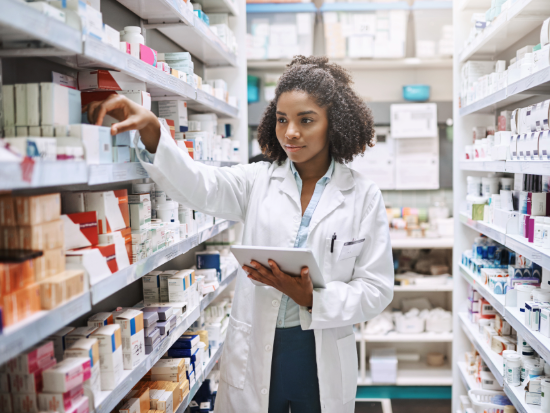 Female pharmacy technician worker reaching for a box of medicine