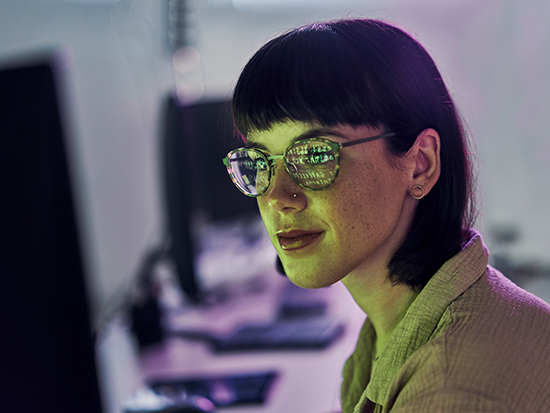 Photo of woman wearing glasses looking at a computer monitor