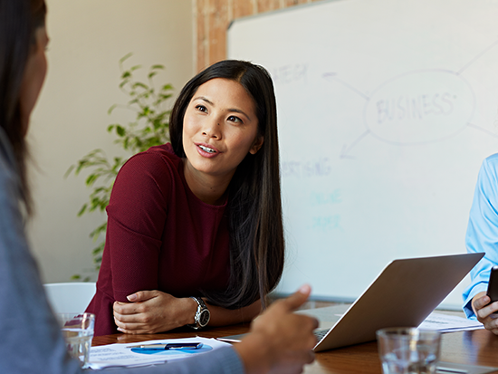 Woman sitting in front of laptop computer leaning on desk