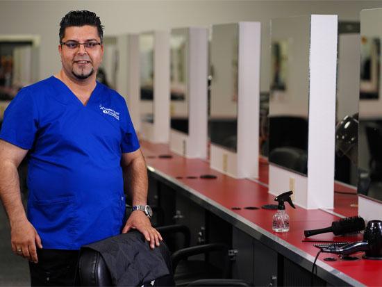 A GateWay student smiling, presenting a barber chair at the one of the Salon Services location.