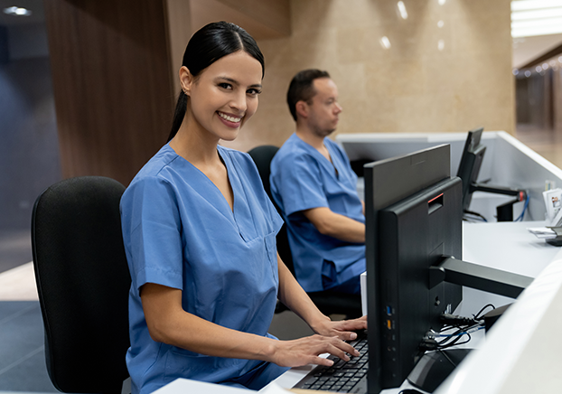 Woman sitting in front of desktop computer smiling while looking at camera